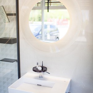 Detail vzorkové koupelny v koupelnovém studiu Gremis - umývací stěna s kulatým zrcadlem