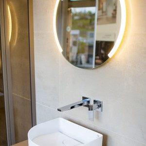 Detail vzorkové koupelny v koupelnovém studiu Gremis - umývací stěna s osvětleným zrcadlem
